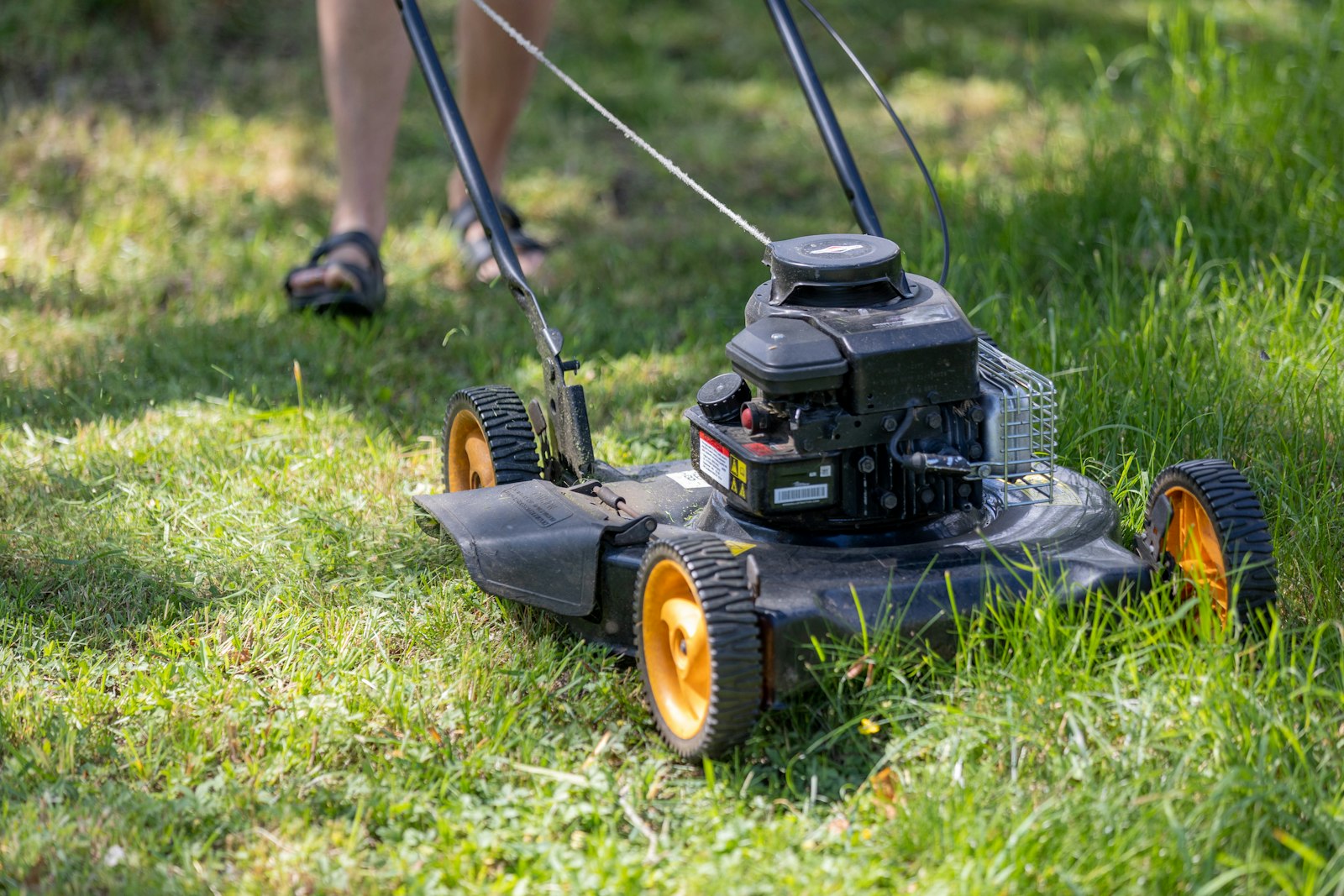 A volunteer mowing a green lawn with a lawn mower