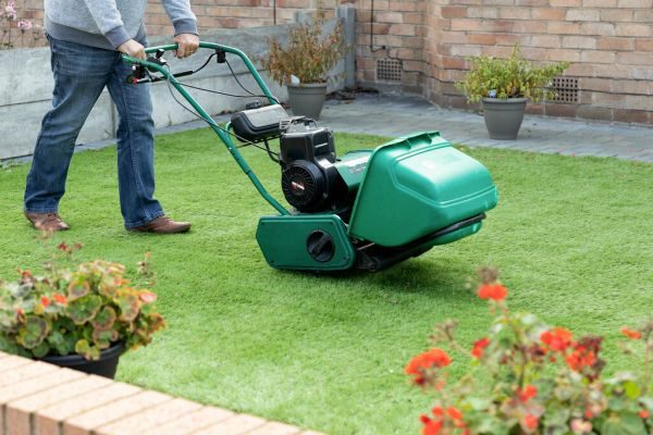 A volunteer mowing an overgrown lawn