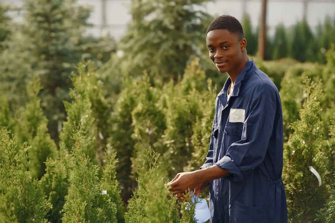 A smiling young gardener tending plants outdoors